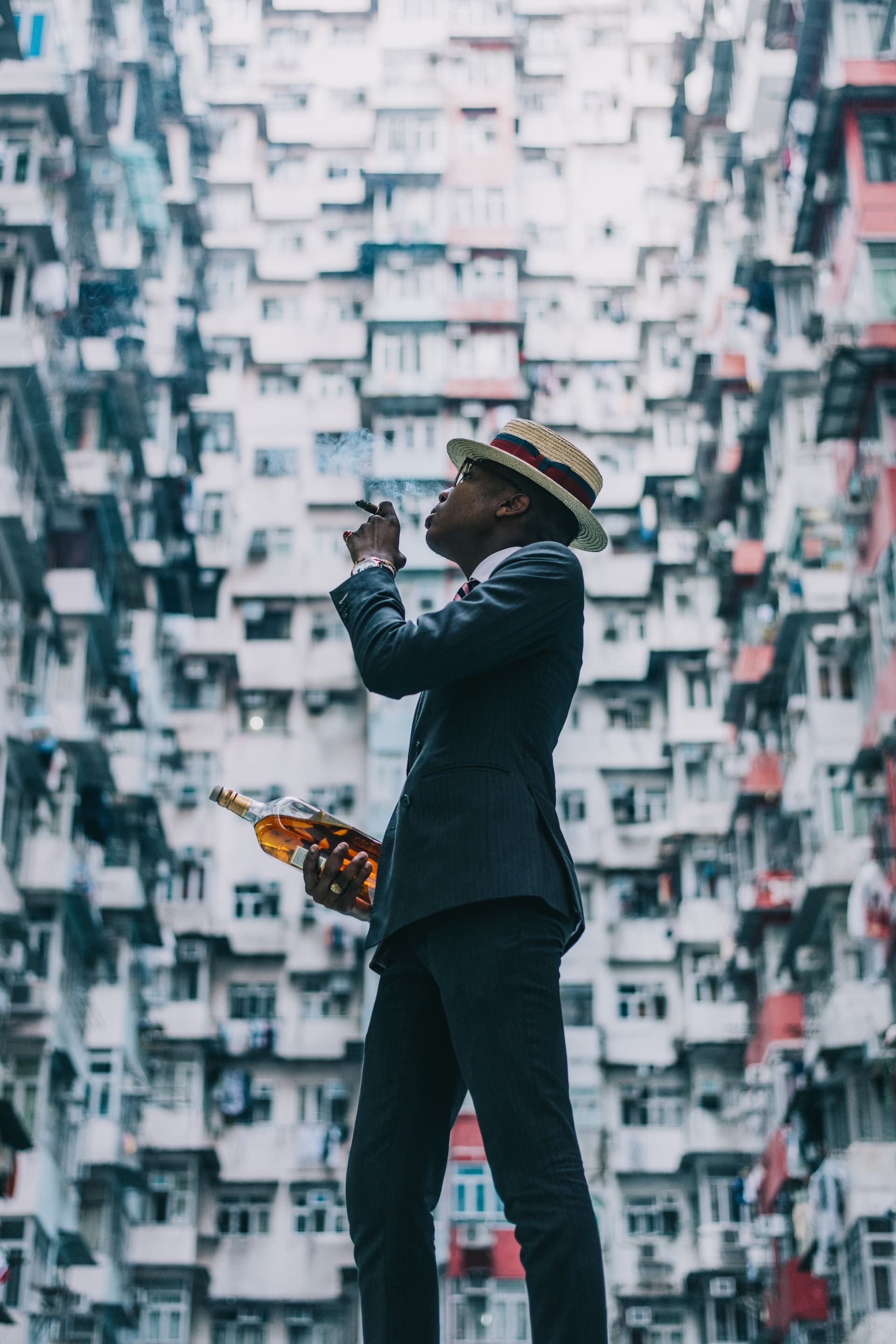 A person standing between buildings and smoking a cigar